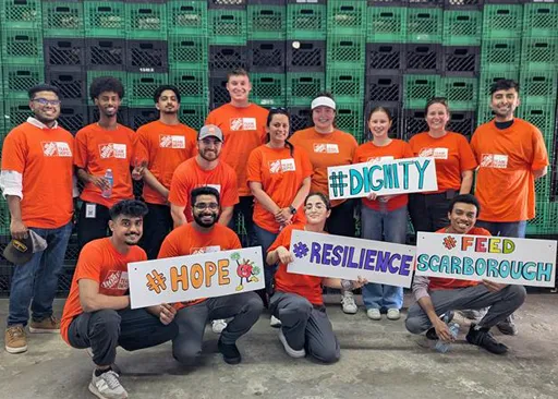 Home Depot Canada associates volunteering together, wearing orange shirts and holding signs promoting hope, dignity, and resilience.