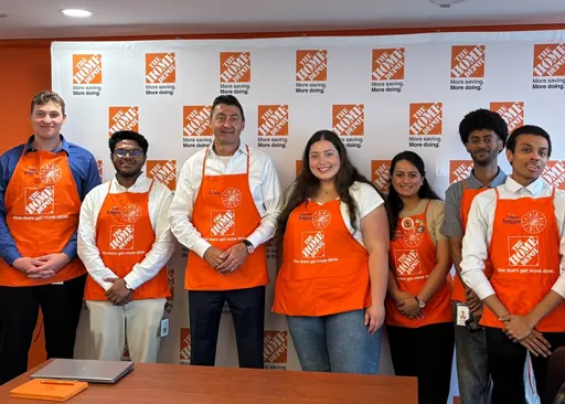 Home Depot Canada early talent team members wearing orange aprons and standing together in front of a Home Depot backdrop.