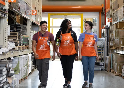 Associés de Home Depot Canada marchant ensemble dans une allée du magasin, illustrant le travail d’équipe et la croissance de carrière en magasin.